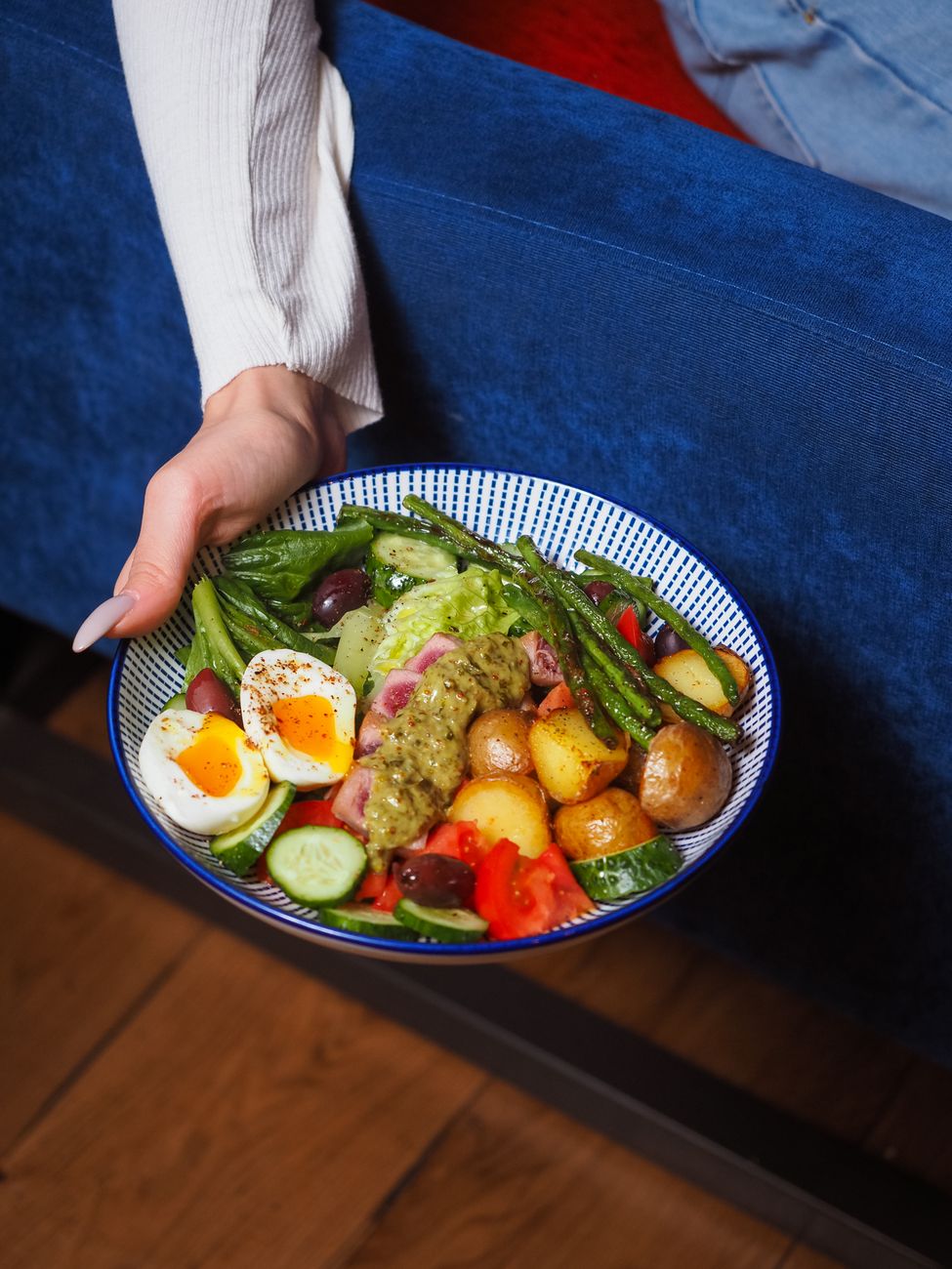 A hand holding a bowl filled with a savory potato dish