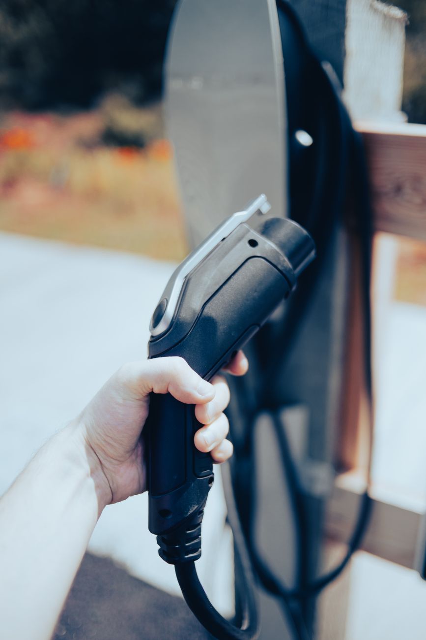 Close-up of a hand holding an EV charging cable outdoors