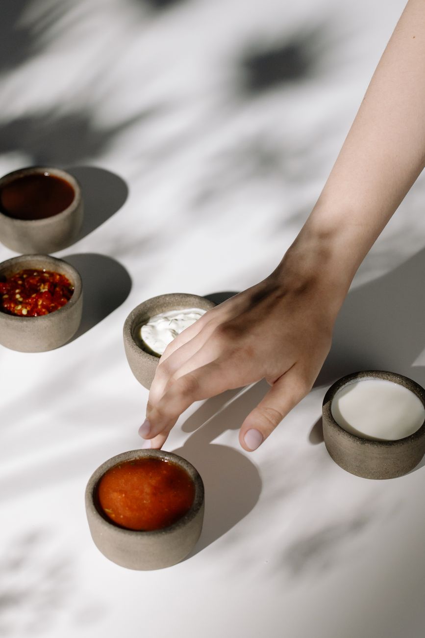 A hand reaching for various sauces in small bowls