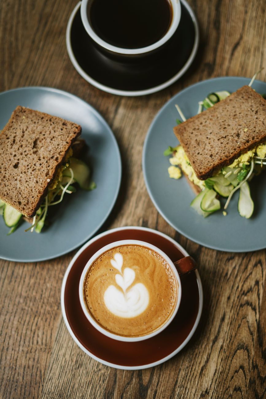 A plate of healthy sandwiches served alongside a cup of coffee