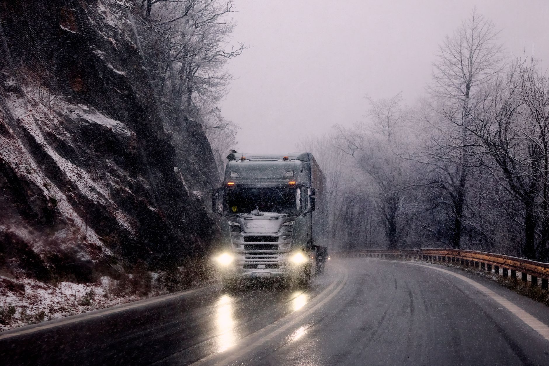 Heavy truck climbing a snow-dusted mountain pass road