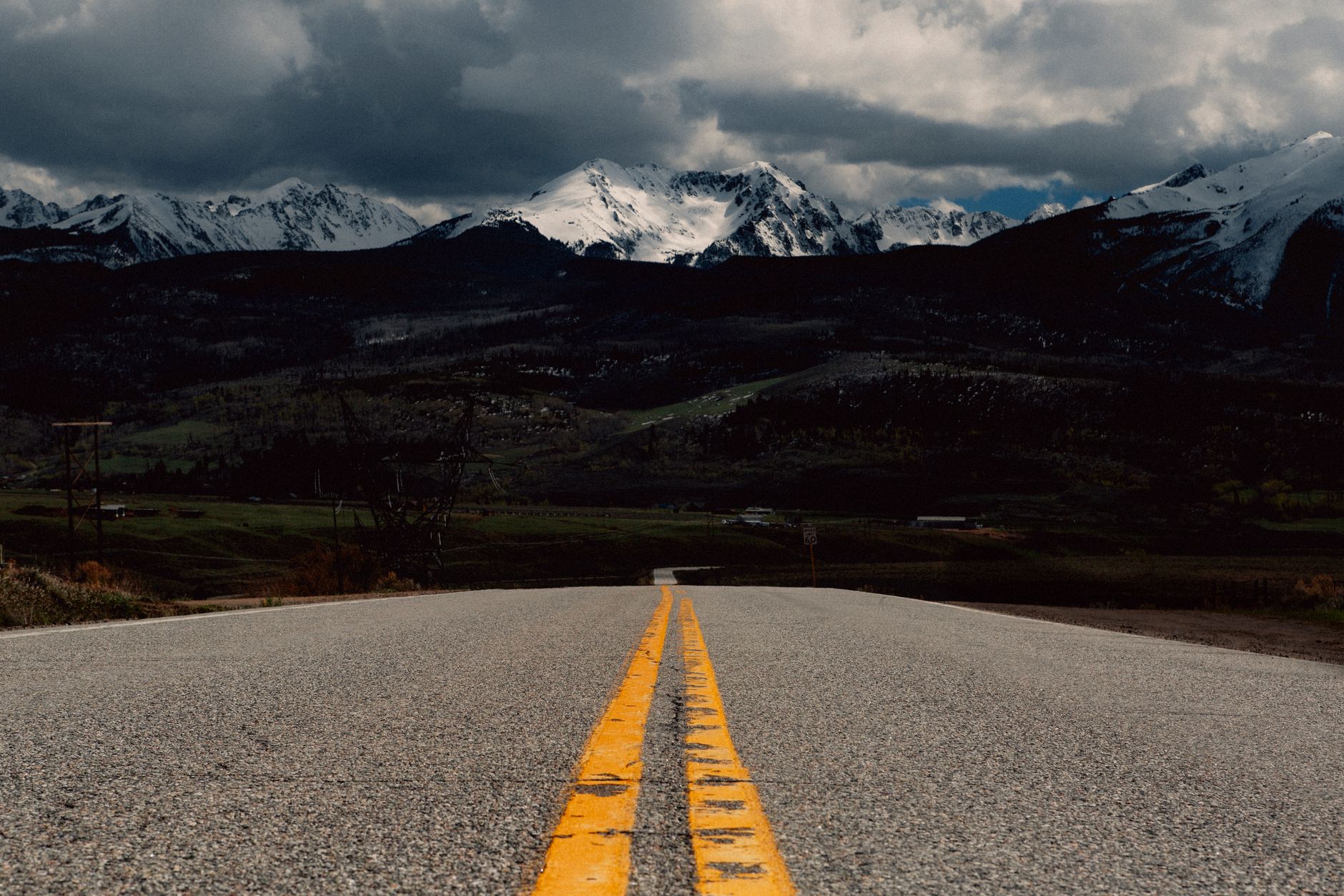 Dramatic view of a highway leading to snow-capped Rocky Mountains