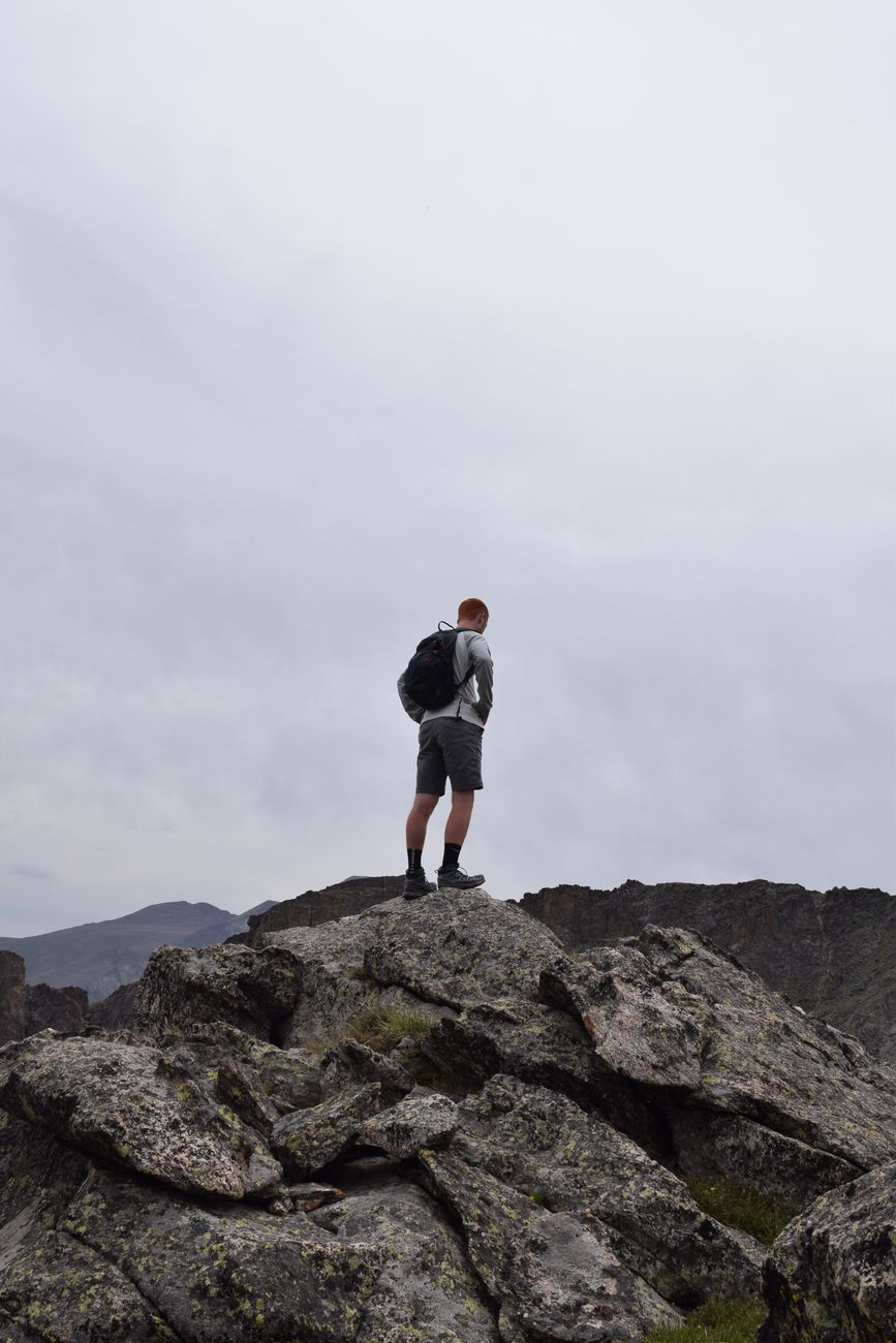 A hiker stands on a rocky peak in Colorado, showcasing advanced alpine terrain