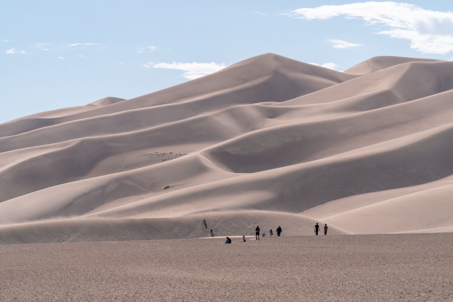 A group of people hiking the striking sand dunes in Colorado under a blue sky
