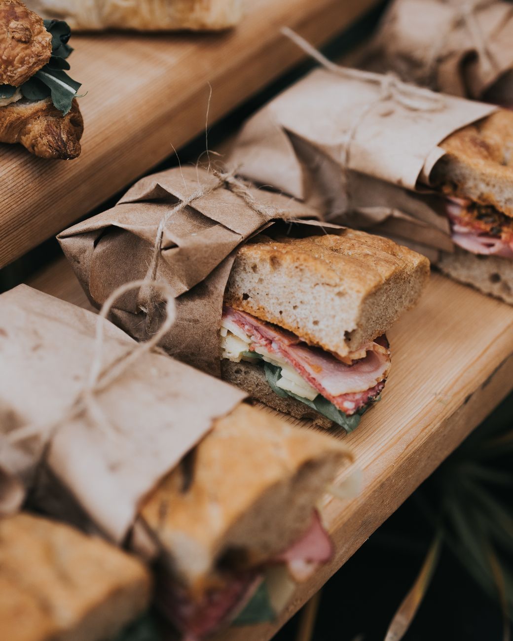 Delicious homemade sandwiches wrapped in rustic paper on a wooden table