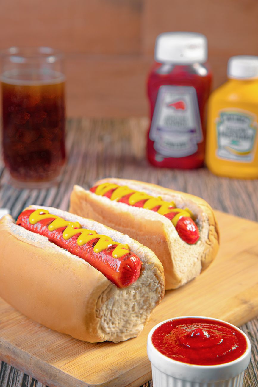 Two hot dogs with ketchup and mustard on a board