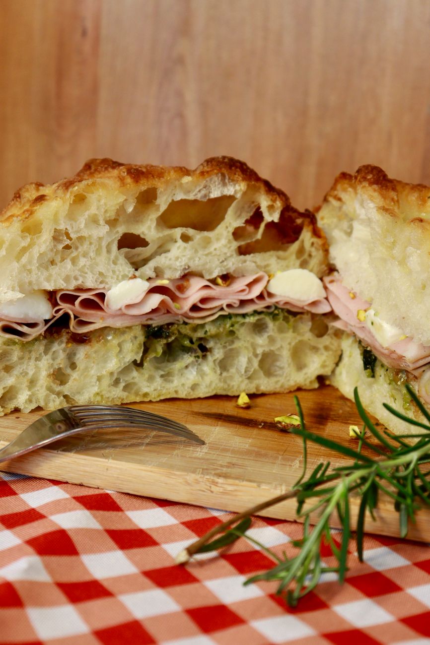 Italian deli sandwich piled with prosciutto, mozzarella, and greens on a fresh roll