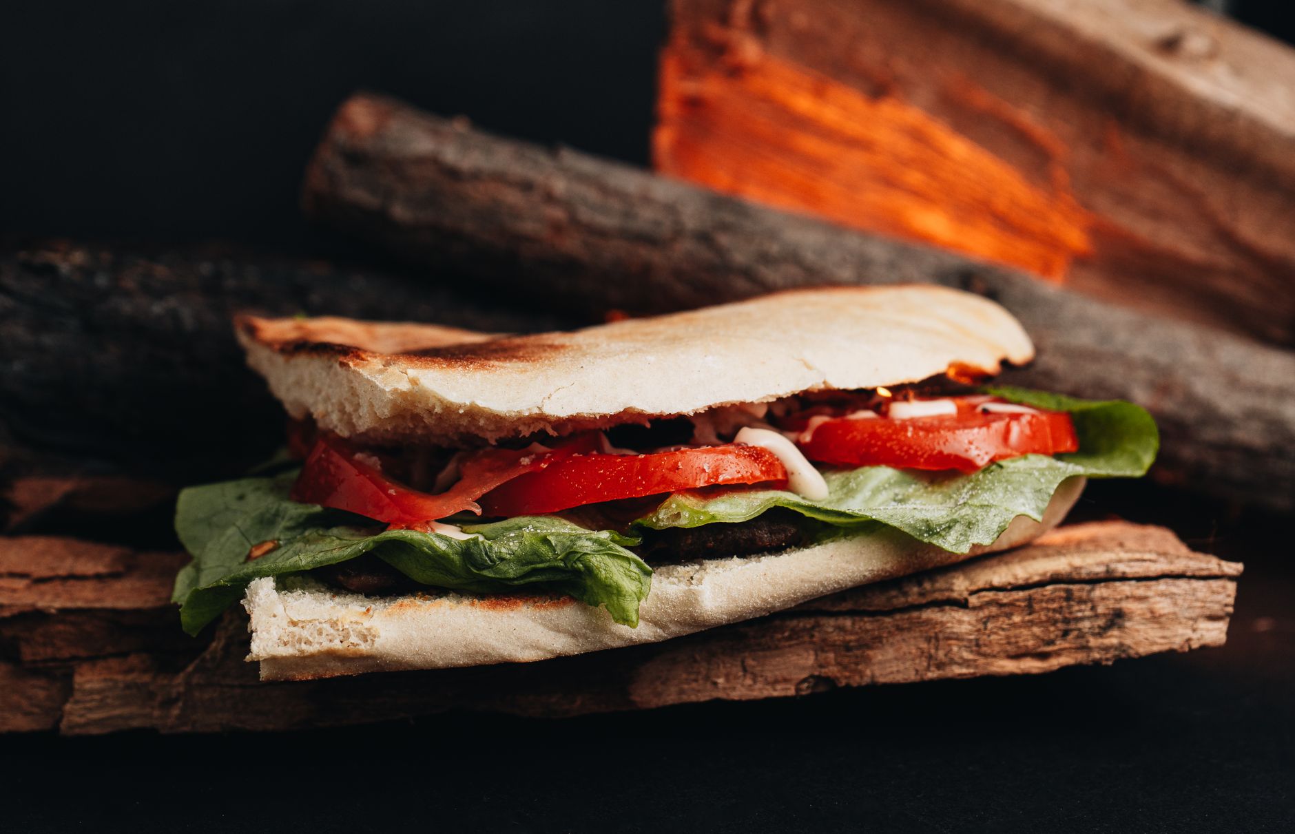 A close-up of an Italian sandwich layered with fresh tomatoes