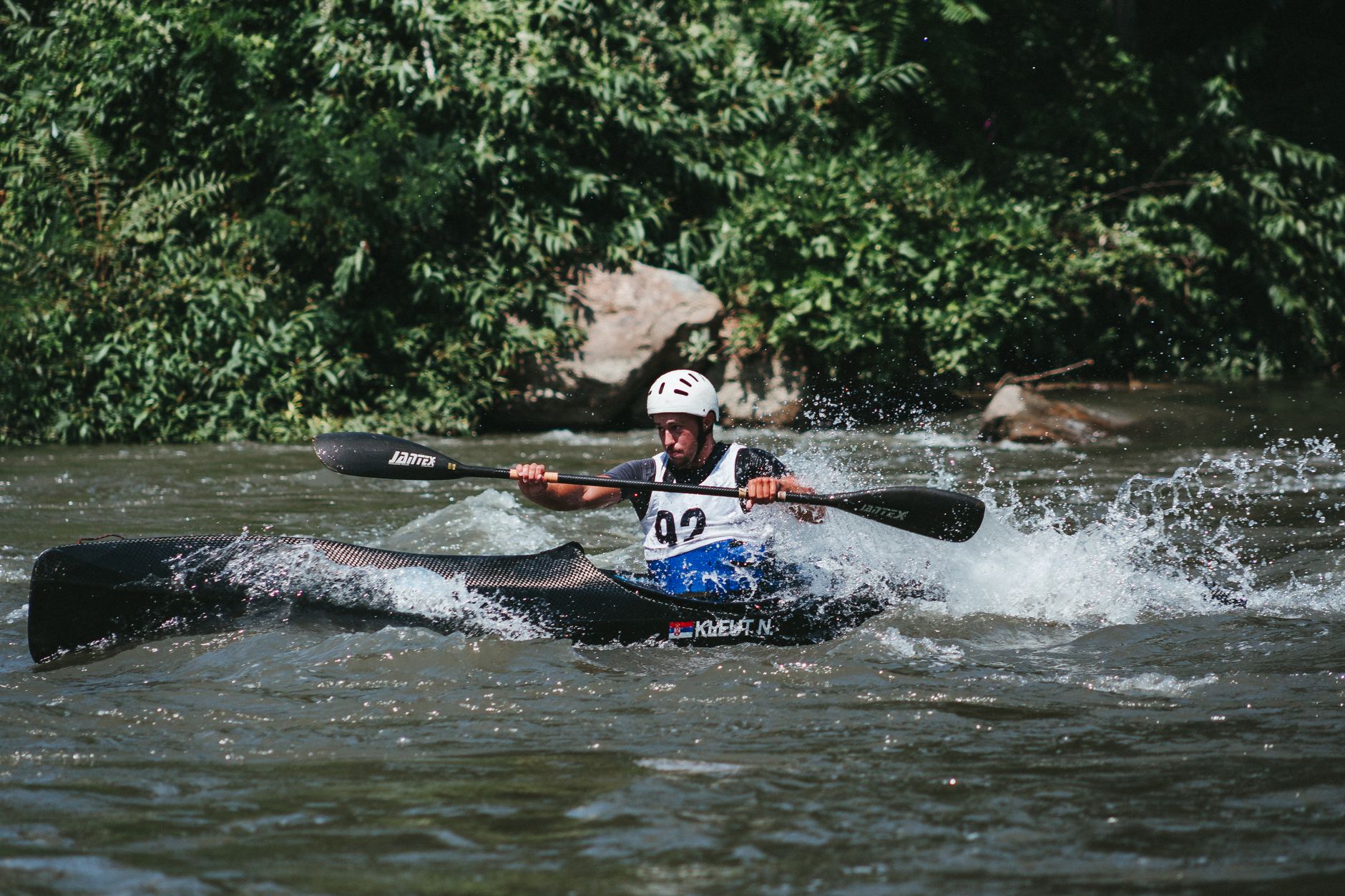 A man kayaking through river rapids with splashing water