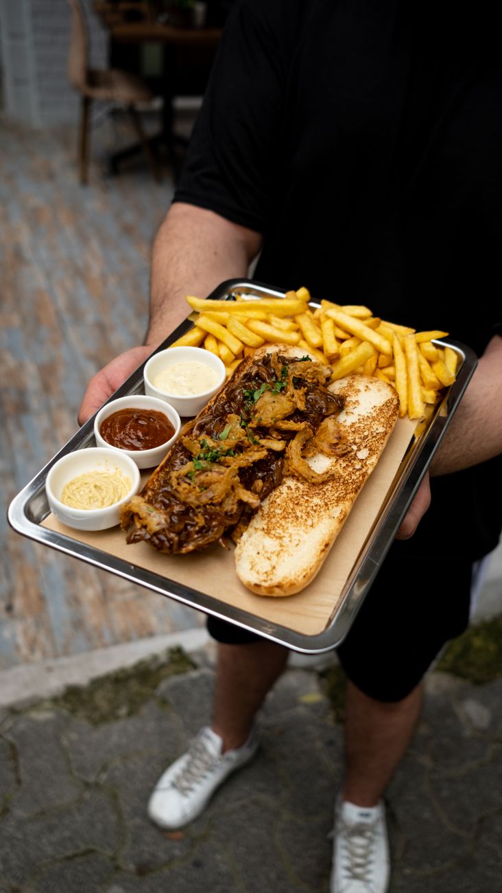 A man holding a tray with a hearty sandwich meal