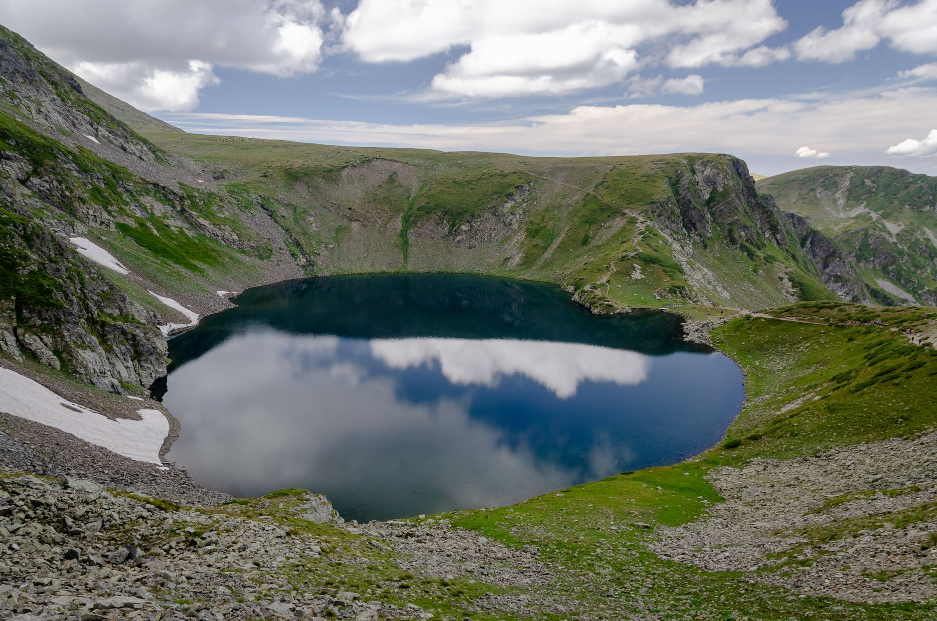 A breathtaking view of a mountain lake reflecting clouds under a summer sky