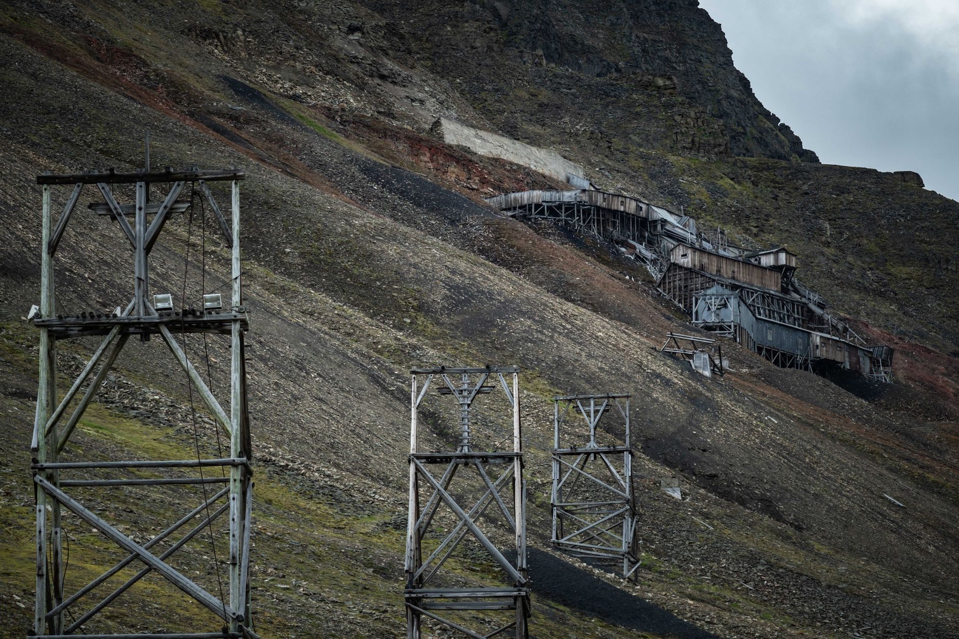 Old mining structures on a rugged mountain slope showcasing industrial history