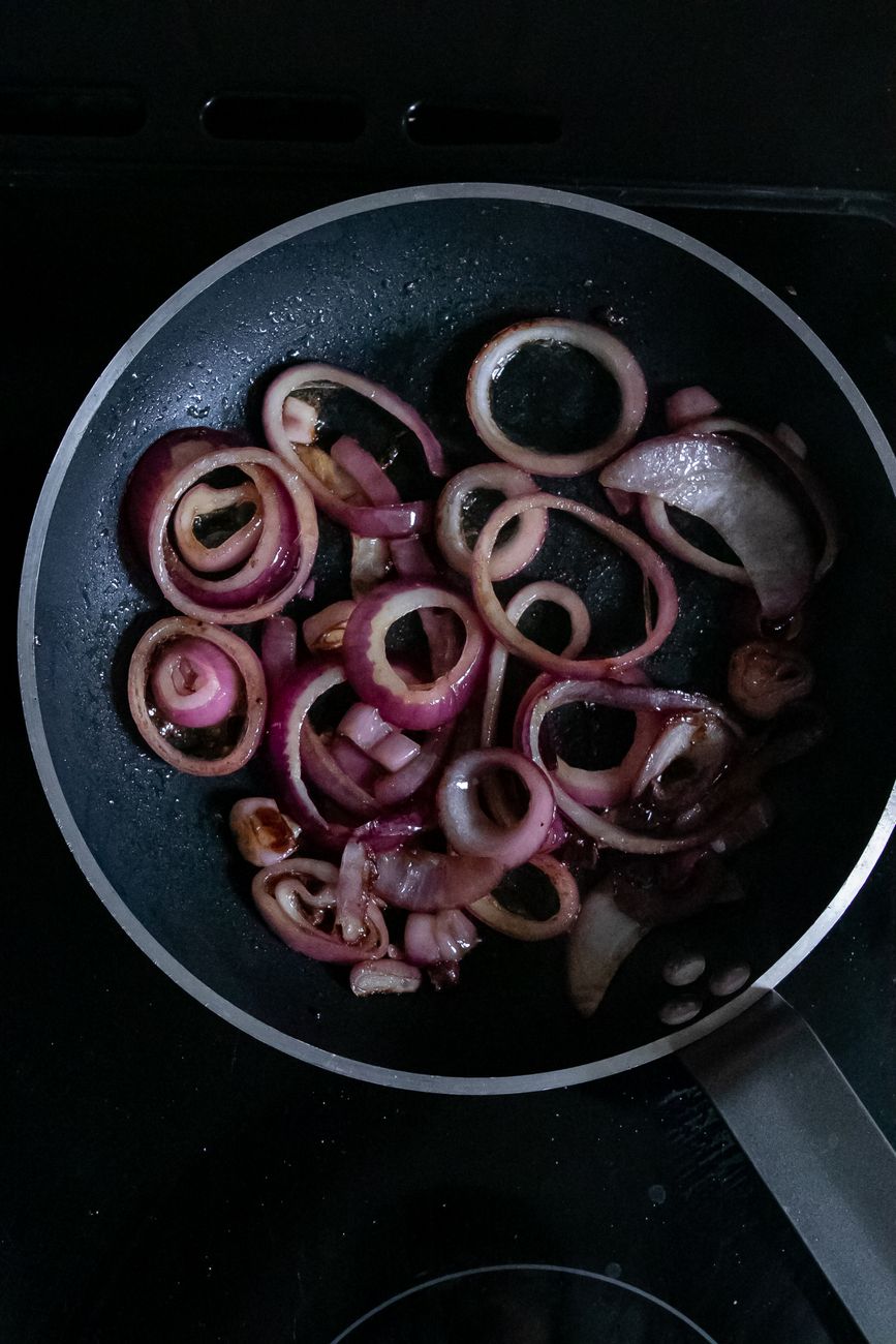 Top view heap of onion rings in a frying pan with oil on a stove