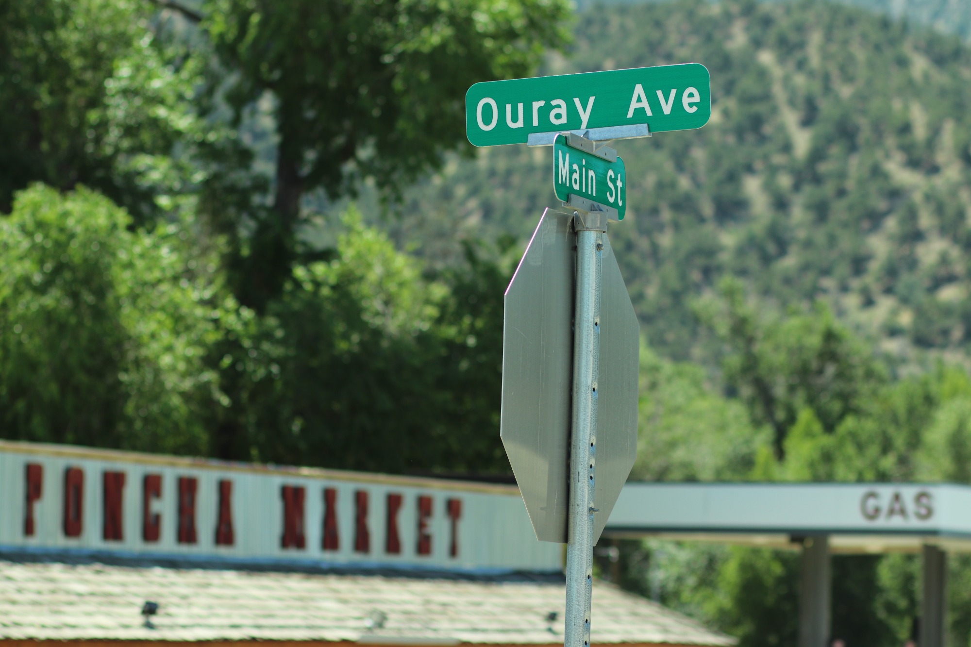 Street sign for the corner of Ouray Avenue and Main Street with Poncha Market visible in the background