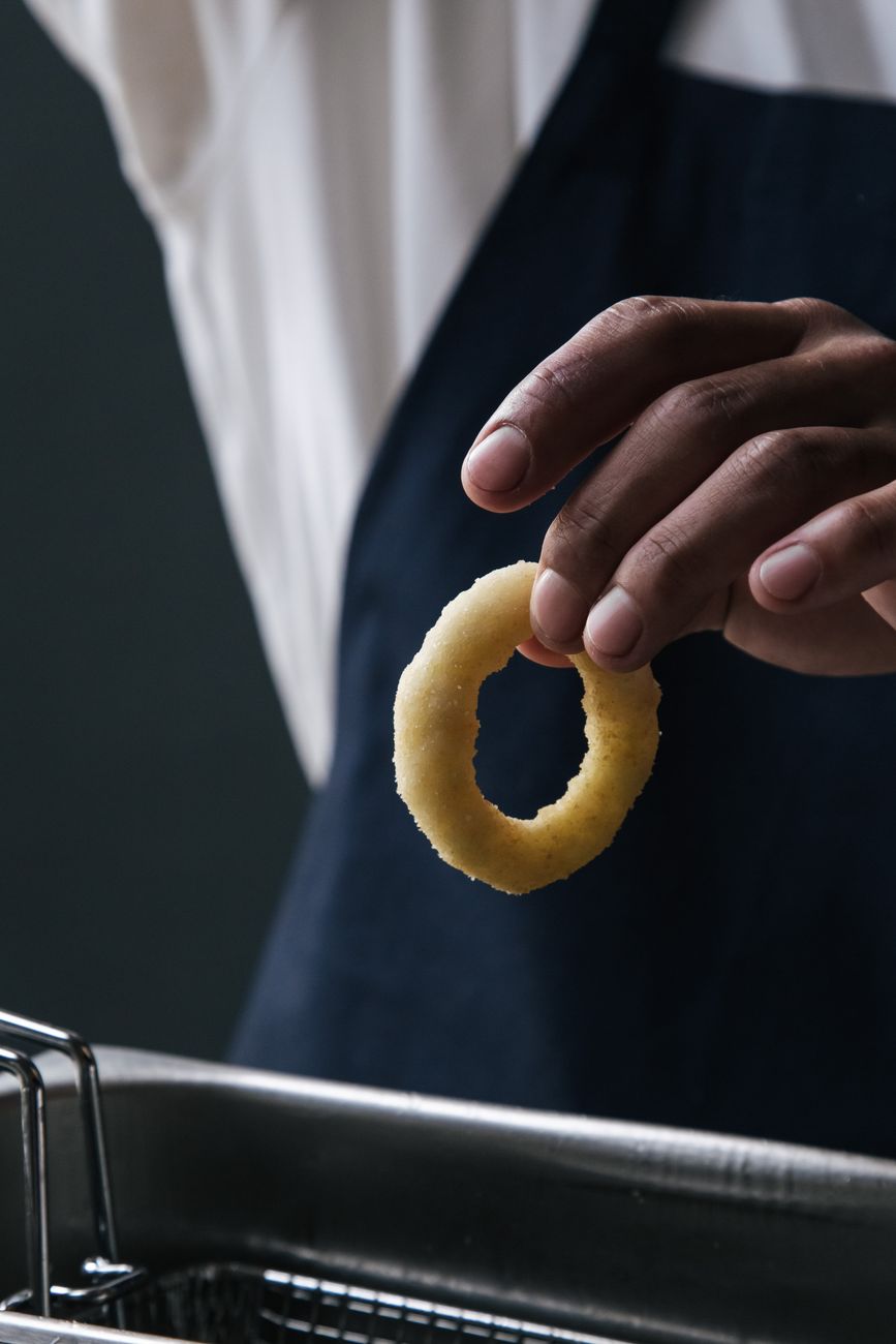 A person holding a crispy fried onion ring