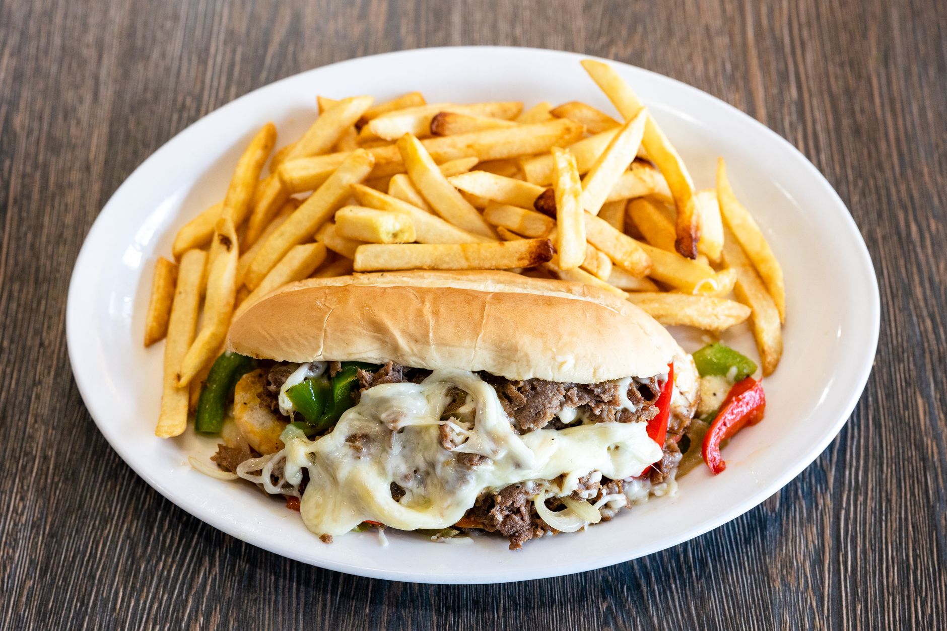 A mouth-watering Philly cheesesteak with melted cheese and french fries