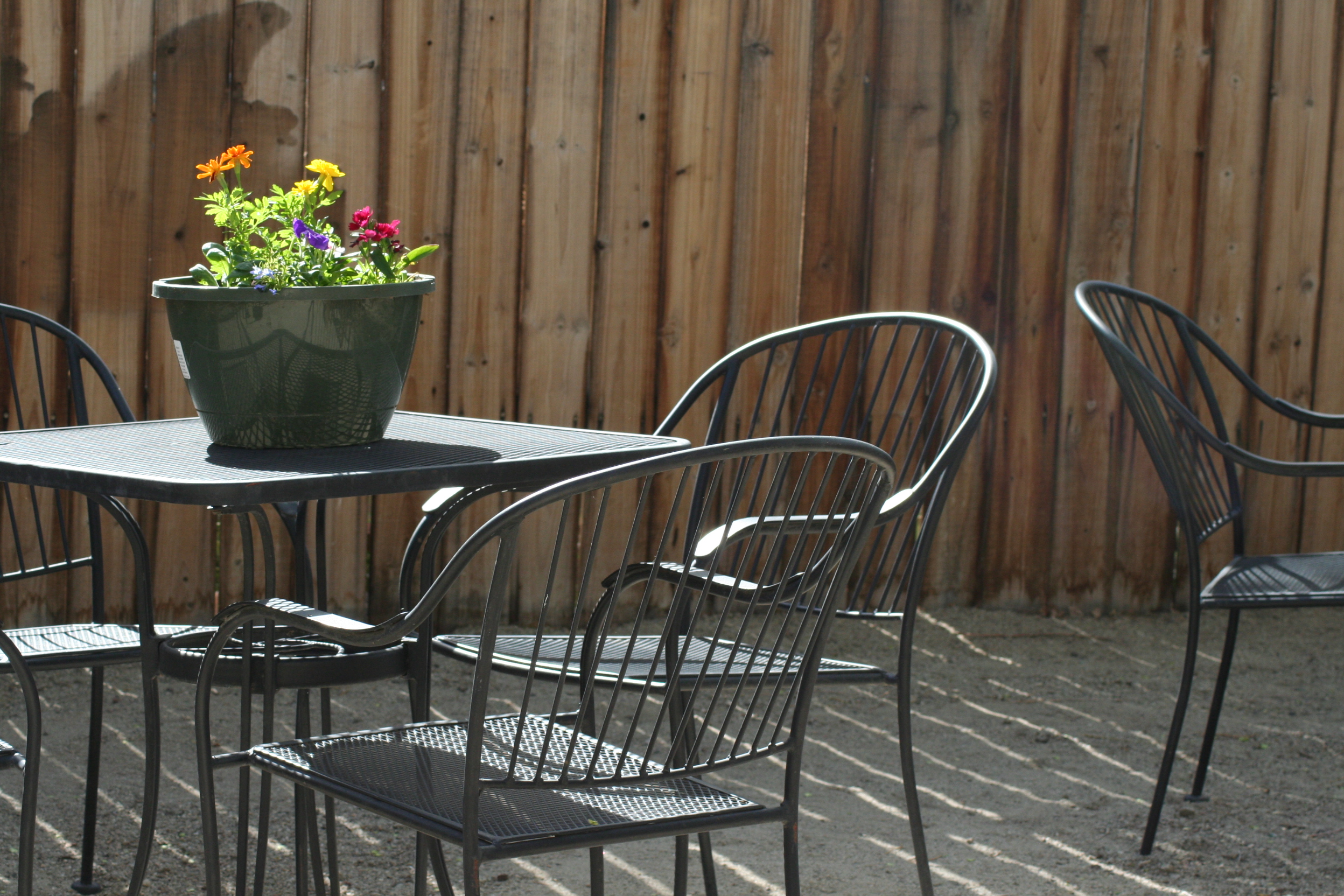 Outdoor metal patio table and chairs with a potted flower arrangement at Poncha Market