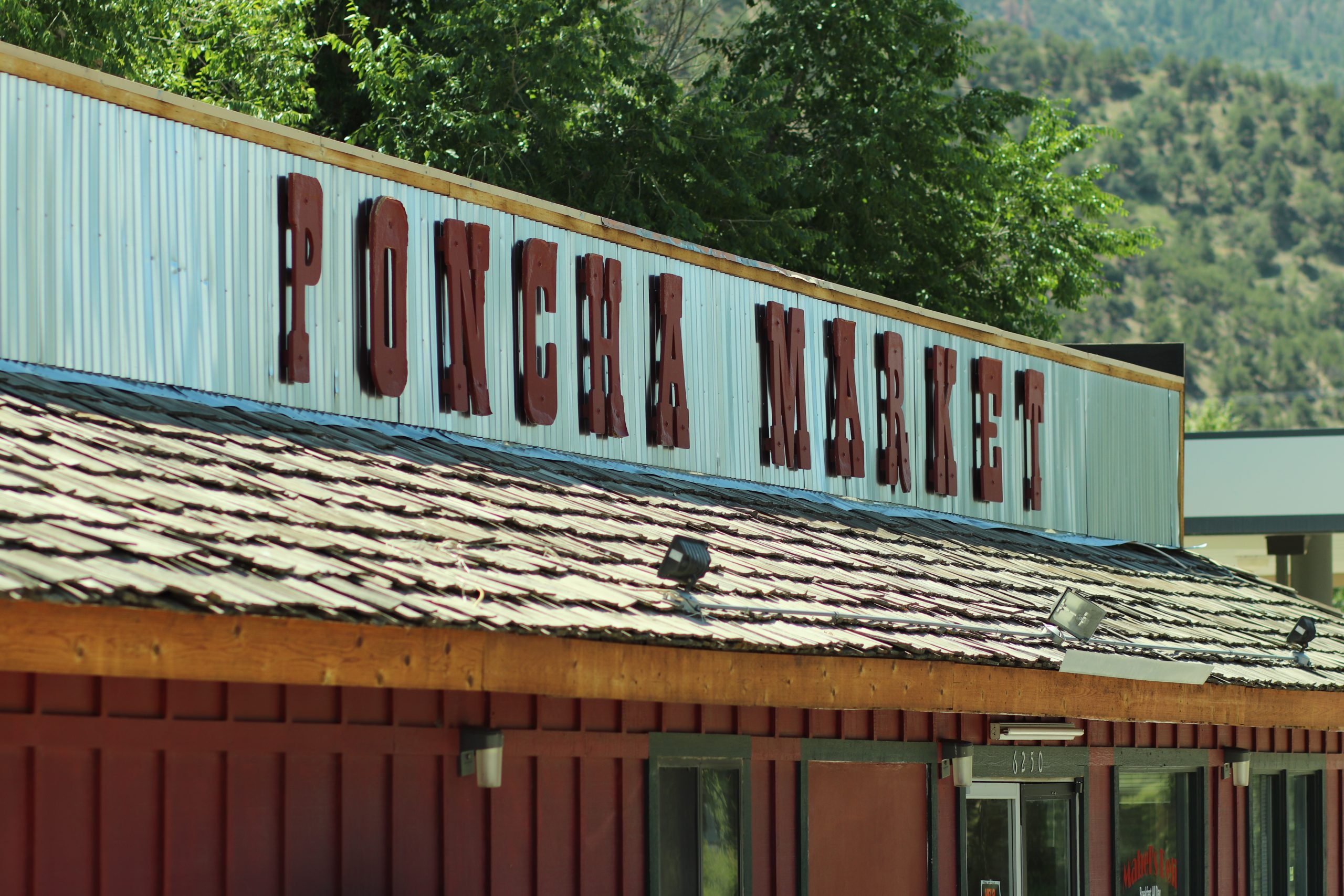 Poncha Market roof sign against a backdrop of Colorado mountains and trees