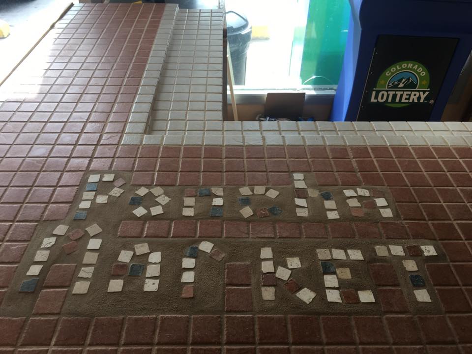 Tile mosaic spelling Poncha Market on the store counter, next to a Colorado Lottery machine