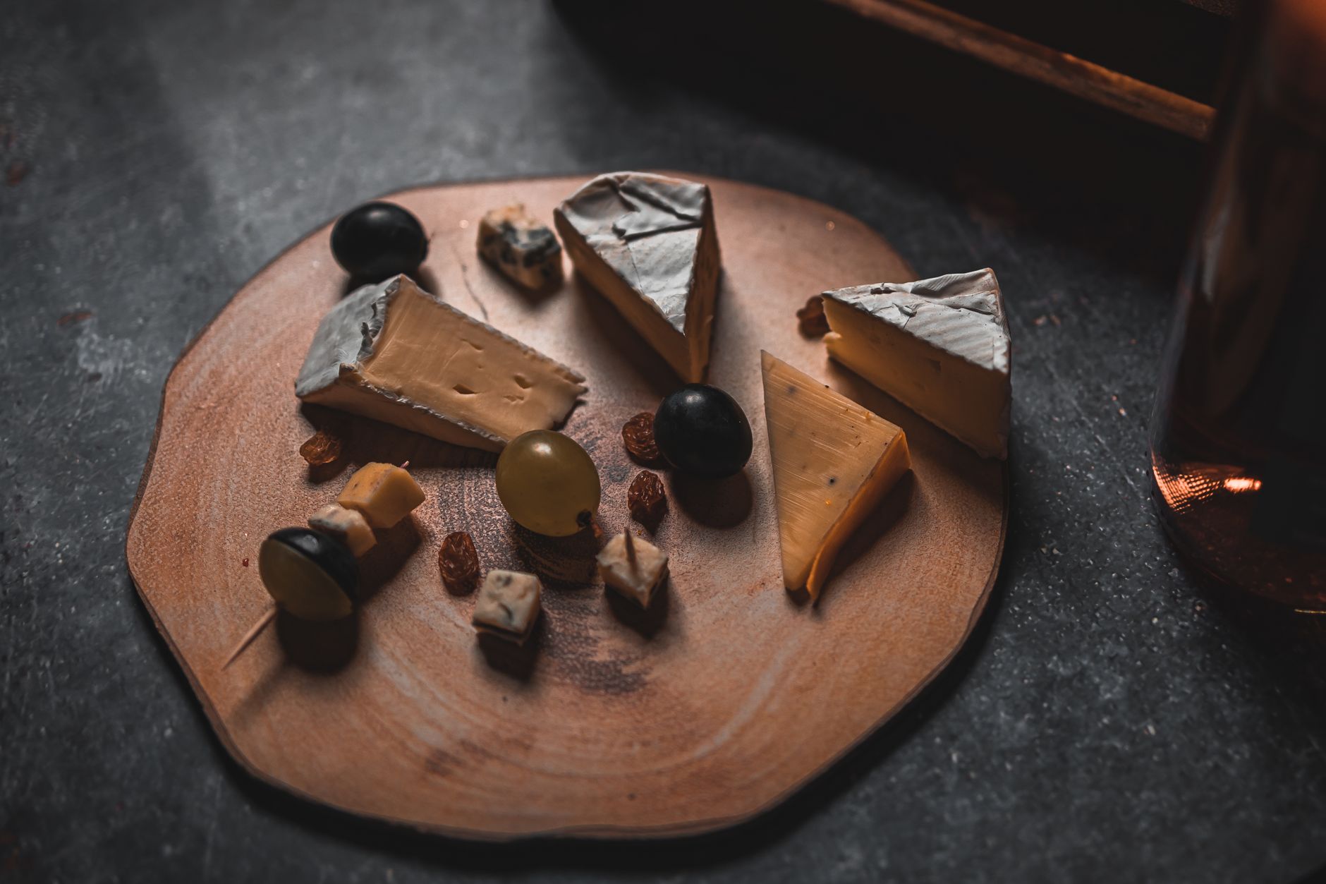A rustic cheese platter with assorted cheeses, nuts, and grapes