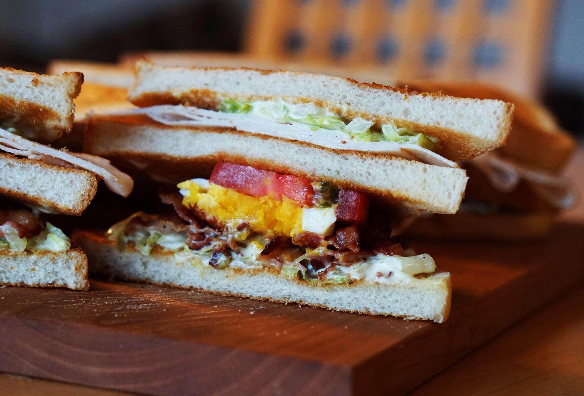 Close-up of a sandwich with egg, bacon, and fresh vegetables on wood