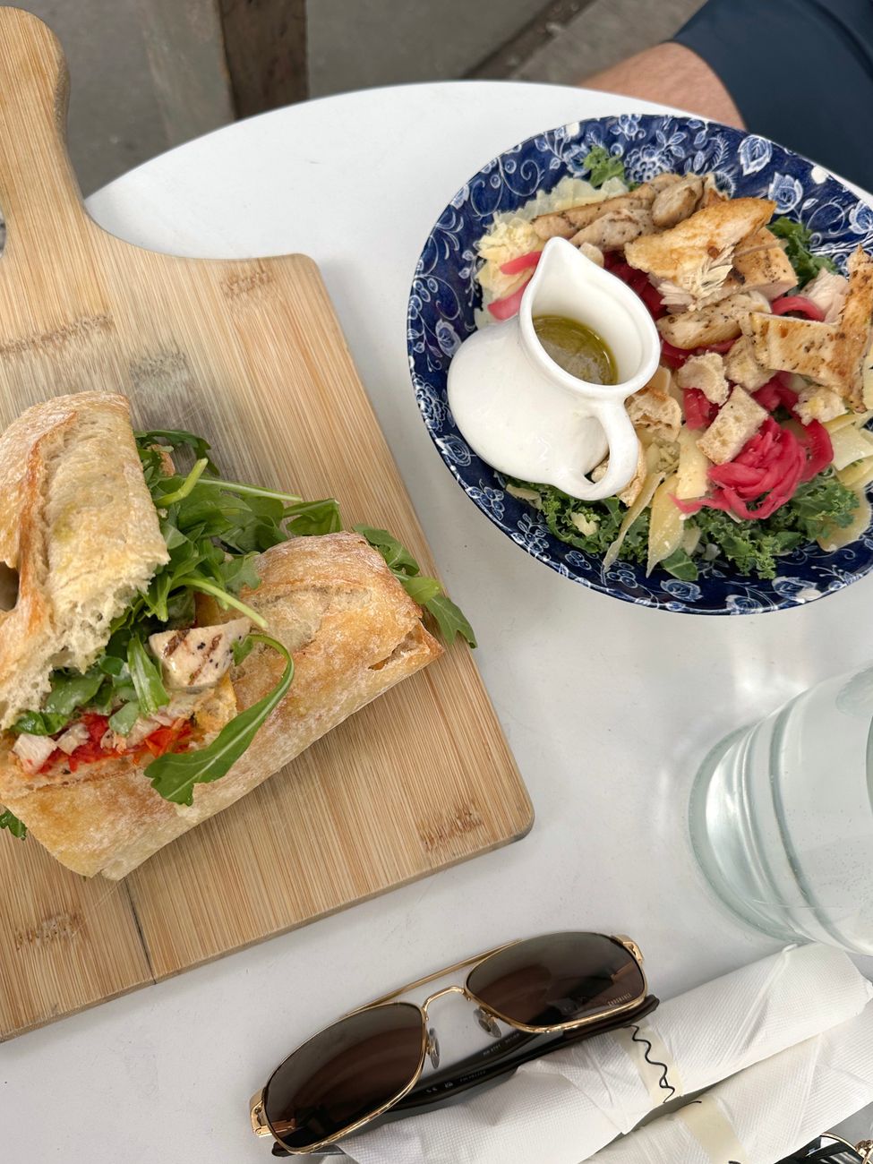 A sandwich and salad served together on a wooden cutting board