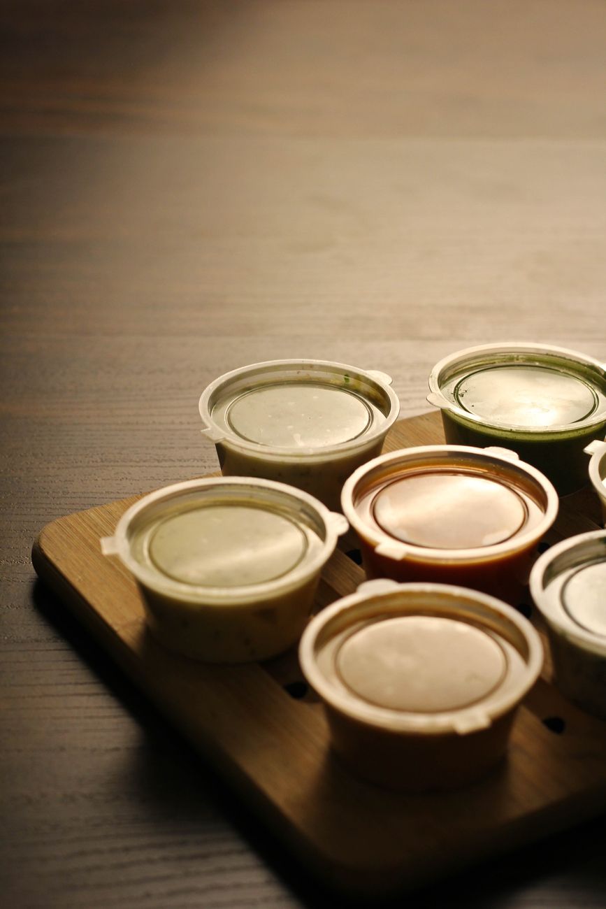 Close-up of various sauces in small containers on a wooden board