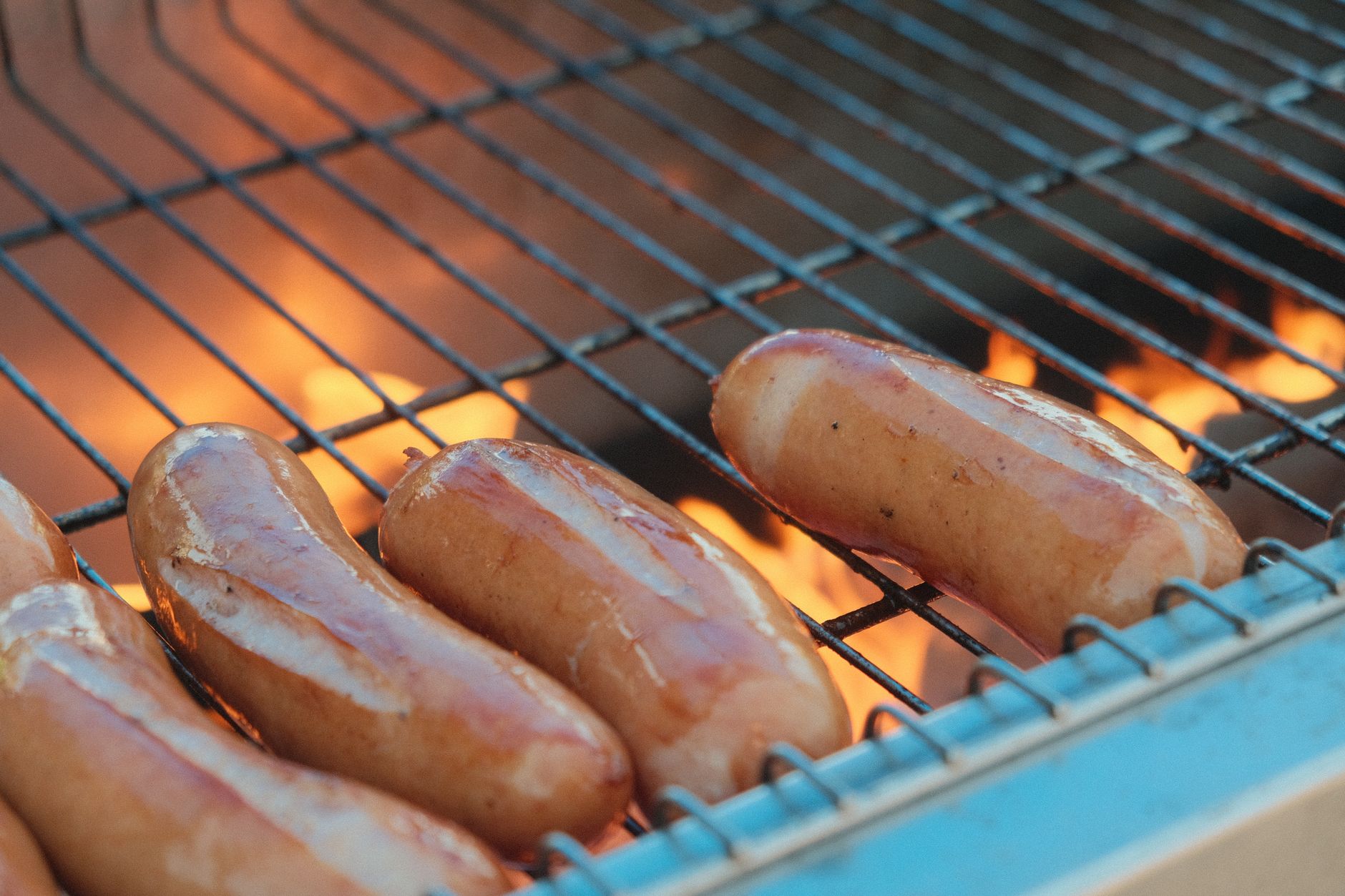 Close-up of juicy sausages grilling over a fiery barbecue