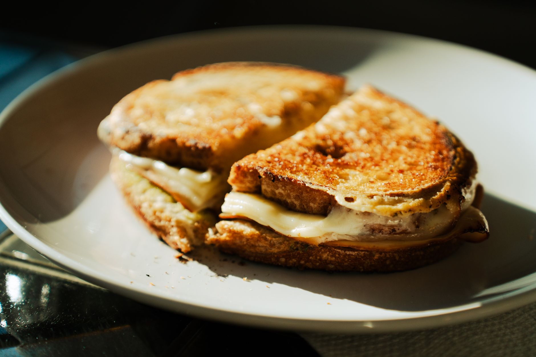 Savory grilled cheese sandwich with melted cheese on a white plate