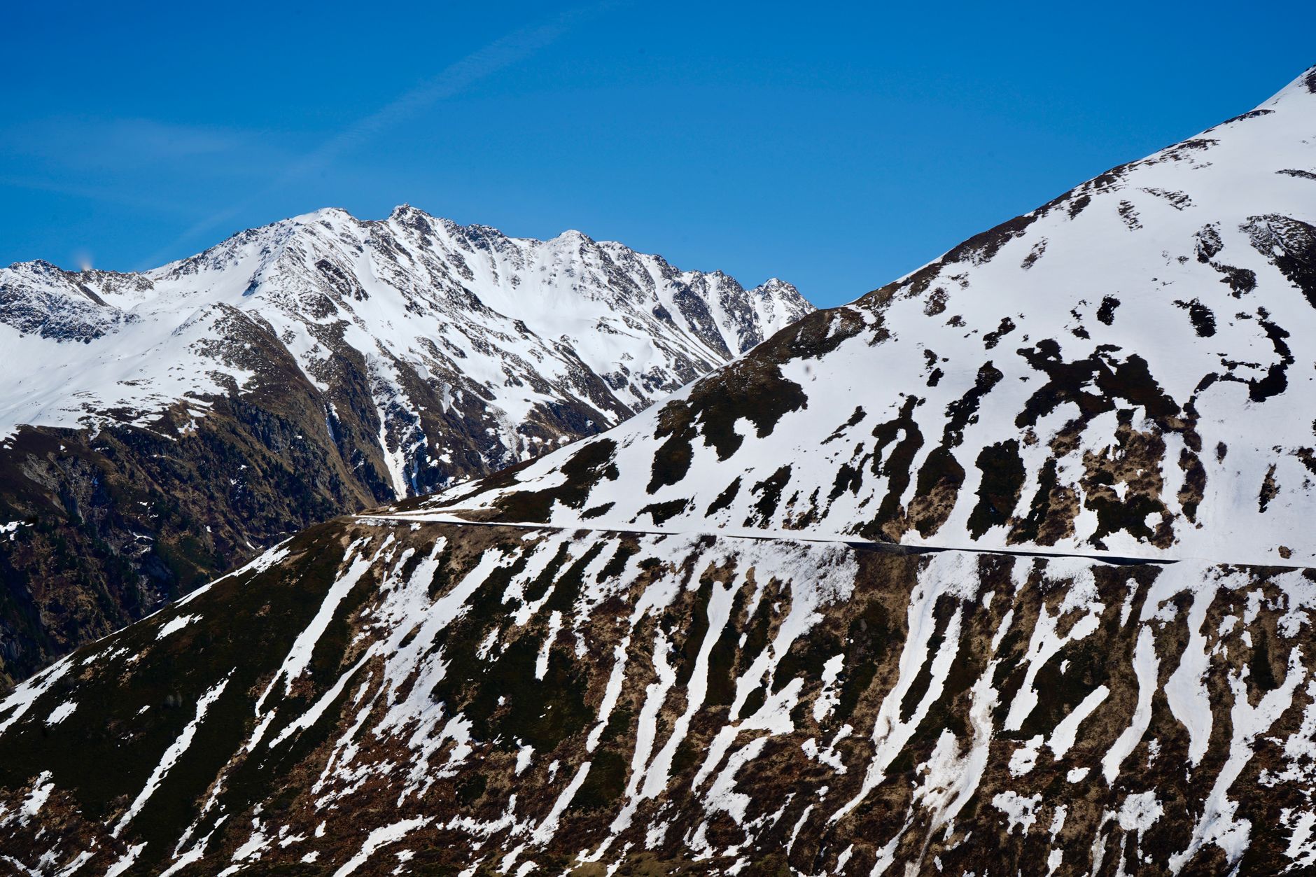 A scenic road winds through snow-covered mountainous terrain