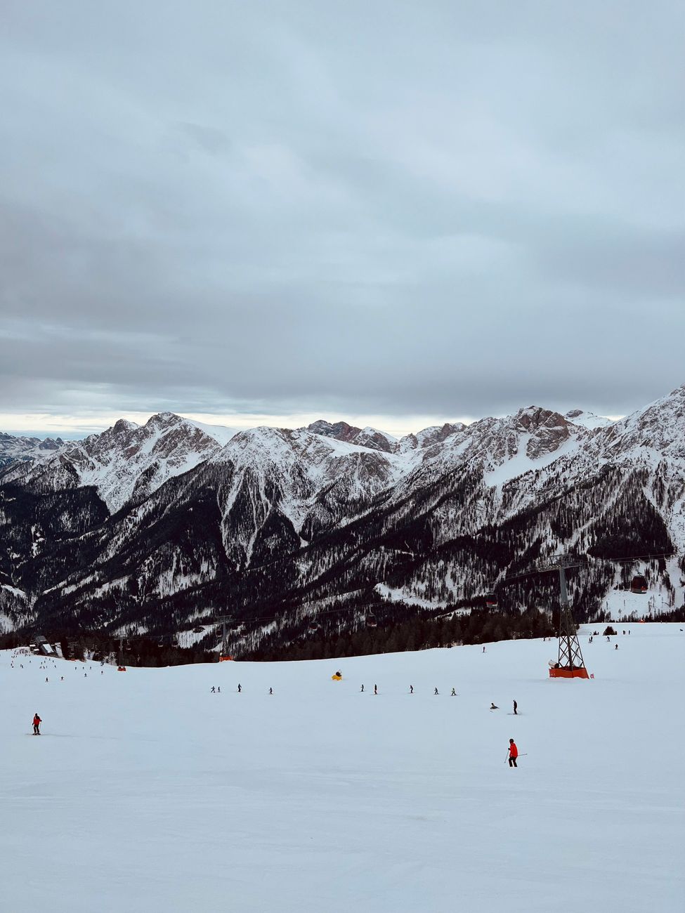 Skiers descending a snowy slope at a mountain ski resort