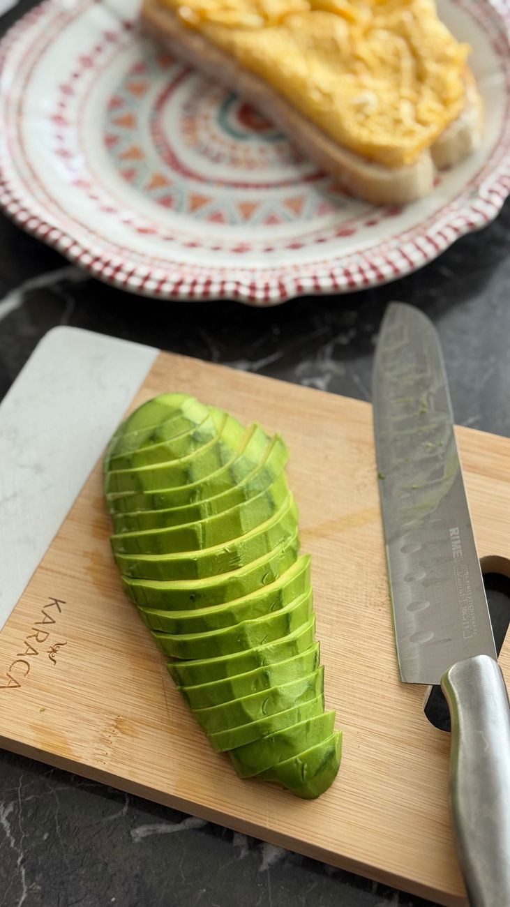 Freshly sliced avocado on a wooden board with bread in the background