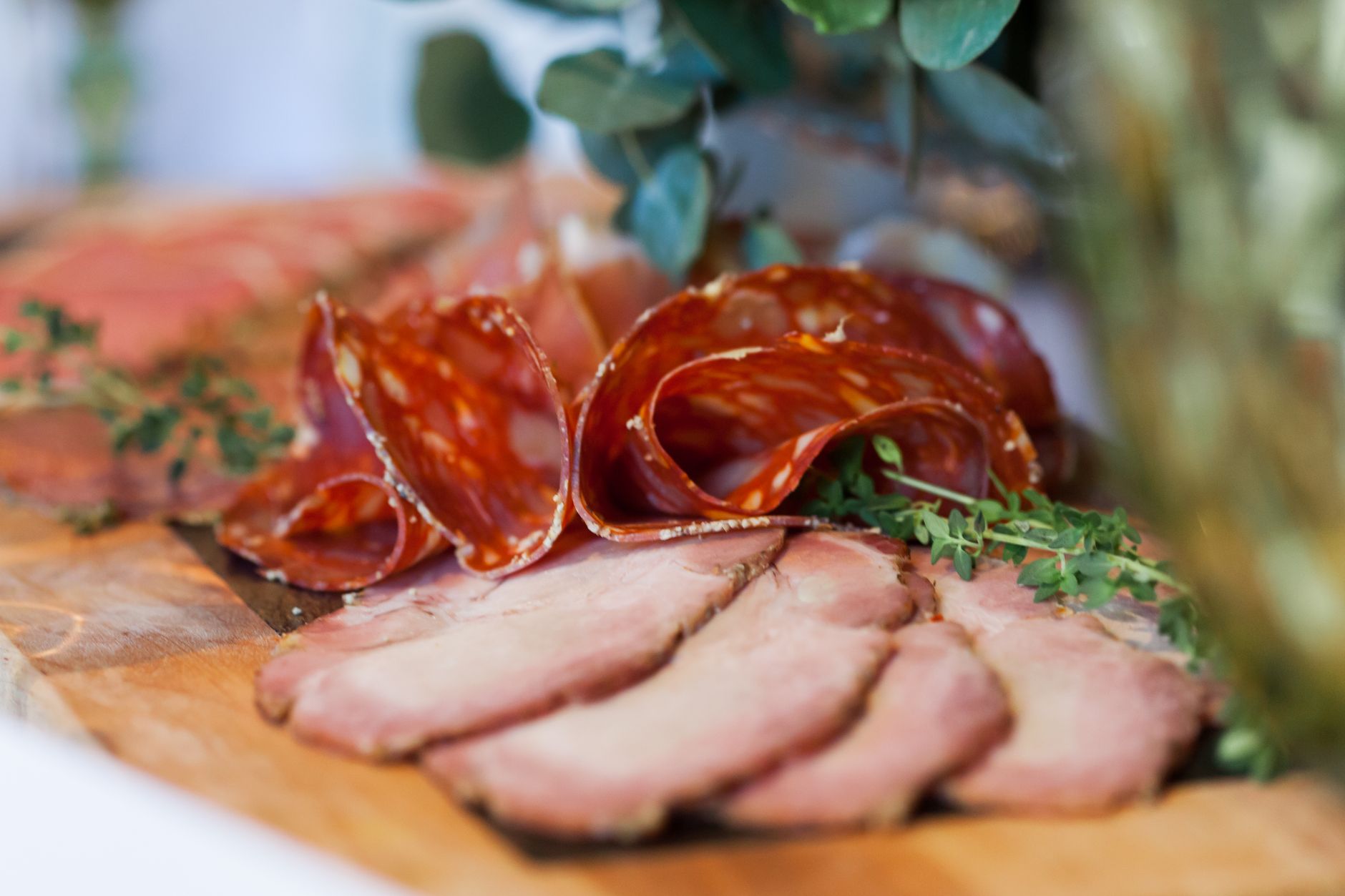 Thin slices of delicatessen salami and smoked meat placed on a wooden table