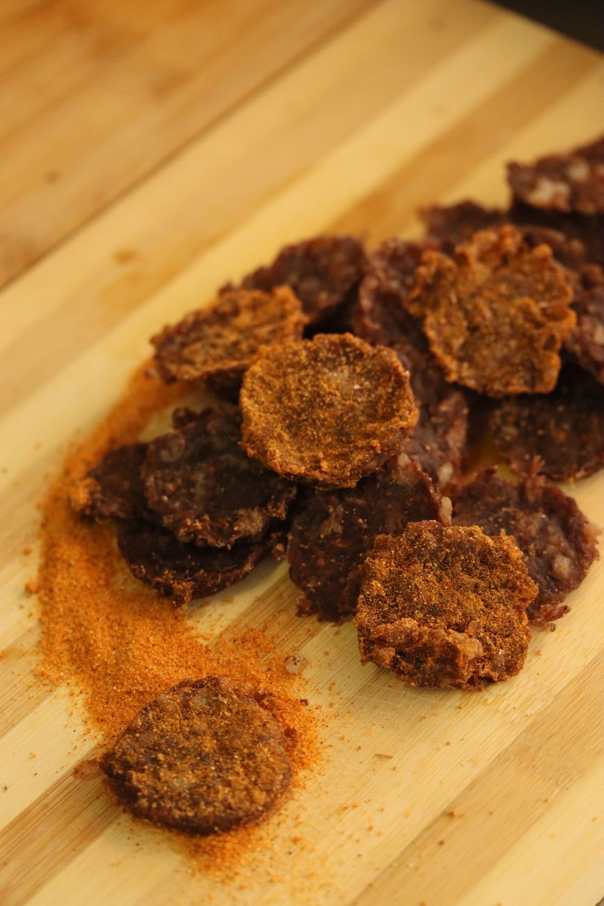 Spiced dried meat slices arranged on a wooden cutting board