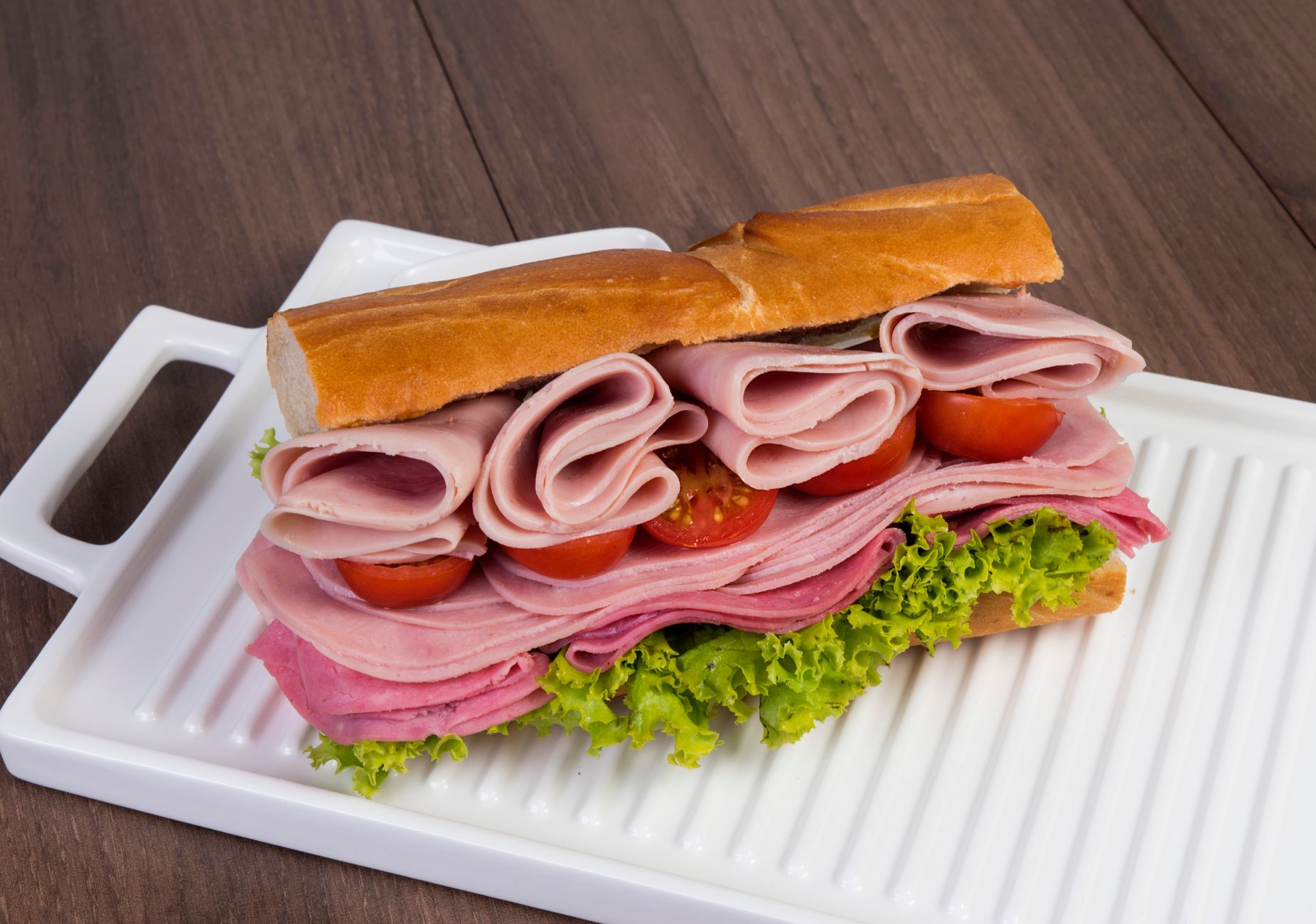 Delicious stacked ham and salami sandwich with lettuce and tomatoes