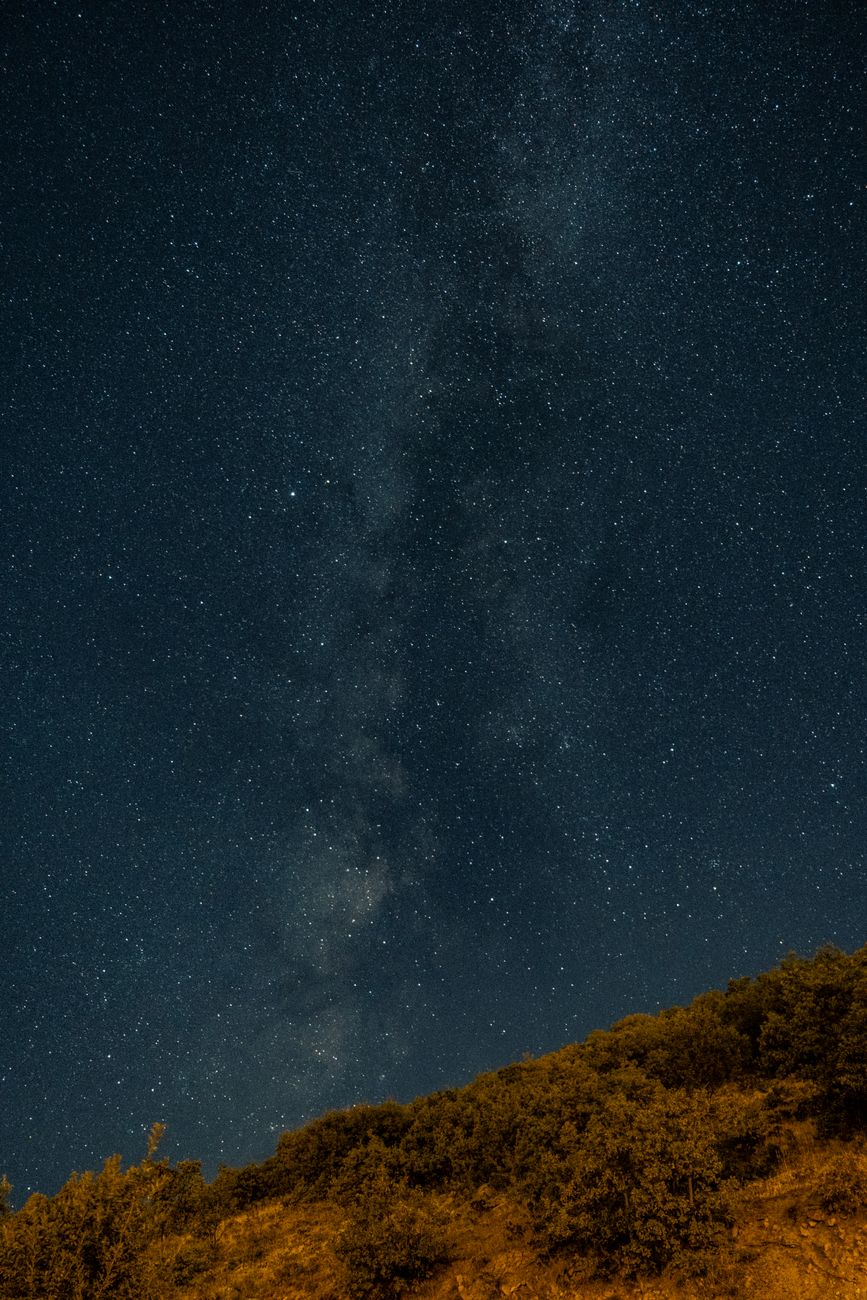 A starry night sky with the Milky Way above silhouetted hills