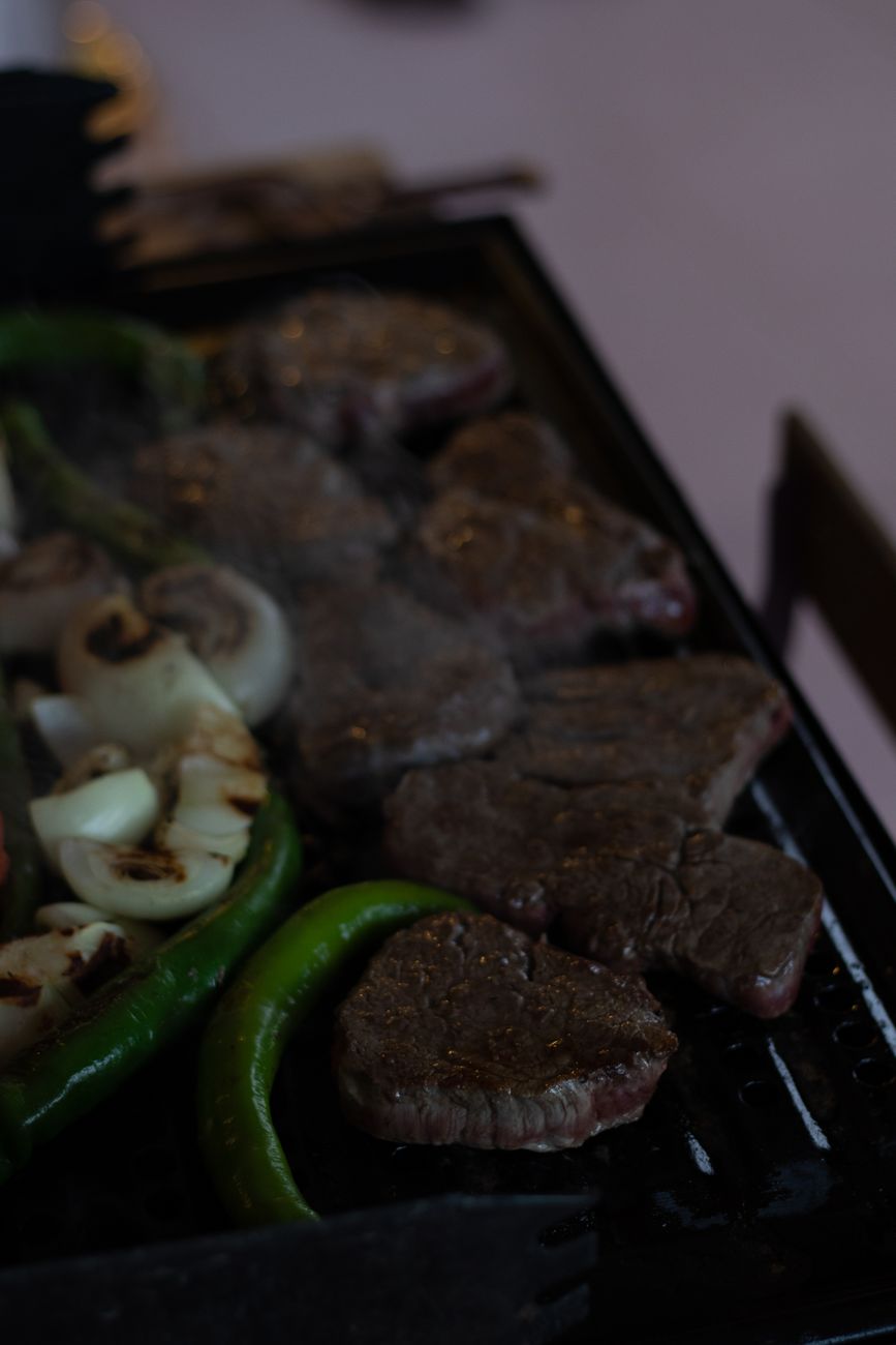 Juicy steaks and vegetables sizzling on an outdoor barbecue grill