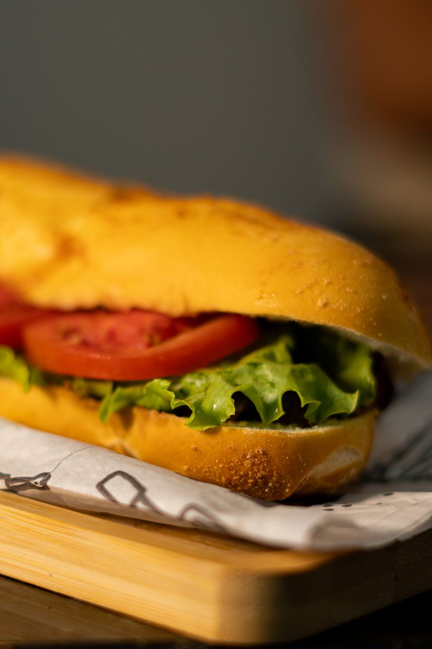 A tasty sub sandwich with fresh lettuce and tomato on a wooden board