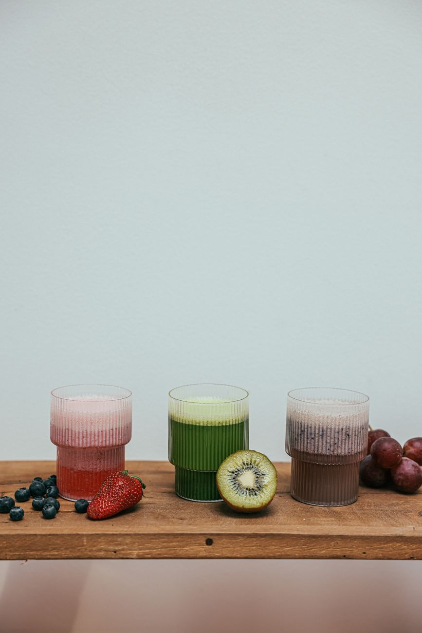 Three vibrant fruit smoothies with fresh fruits on a wooden table