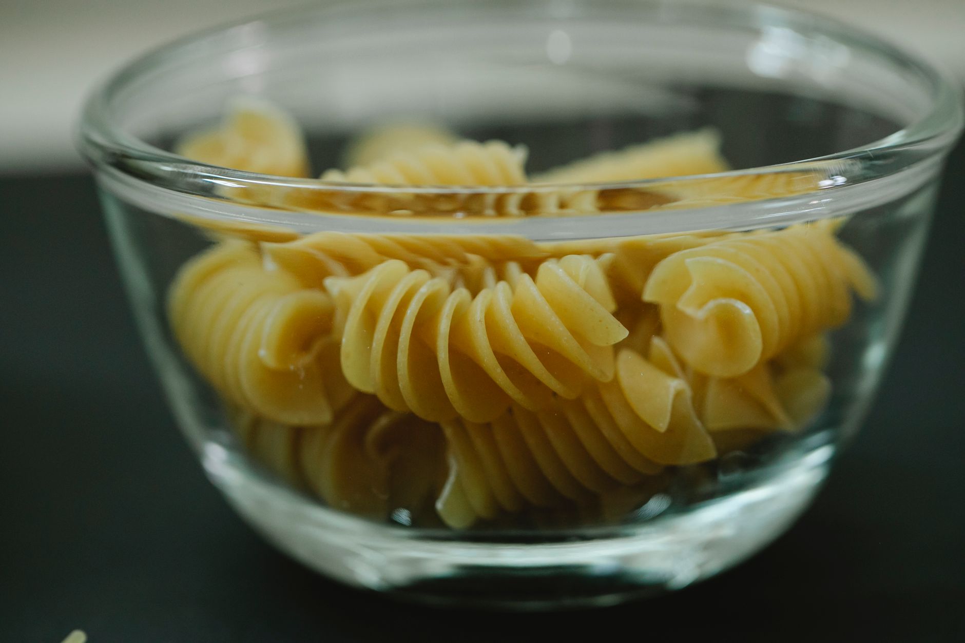 A glass bowl filled with twirl macaroni pasta