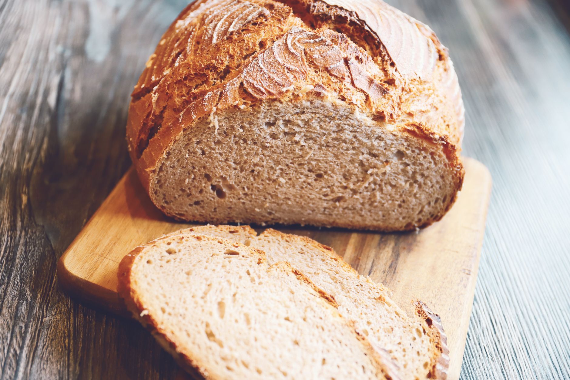 Freshly baked rustic whole wheat bread loaf with slices on a wooden board