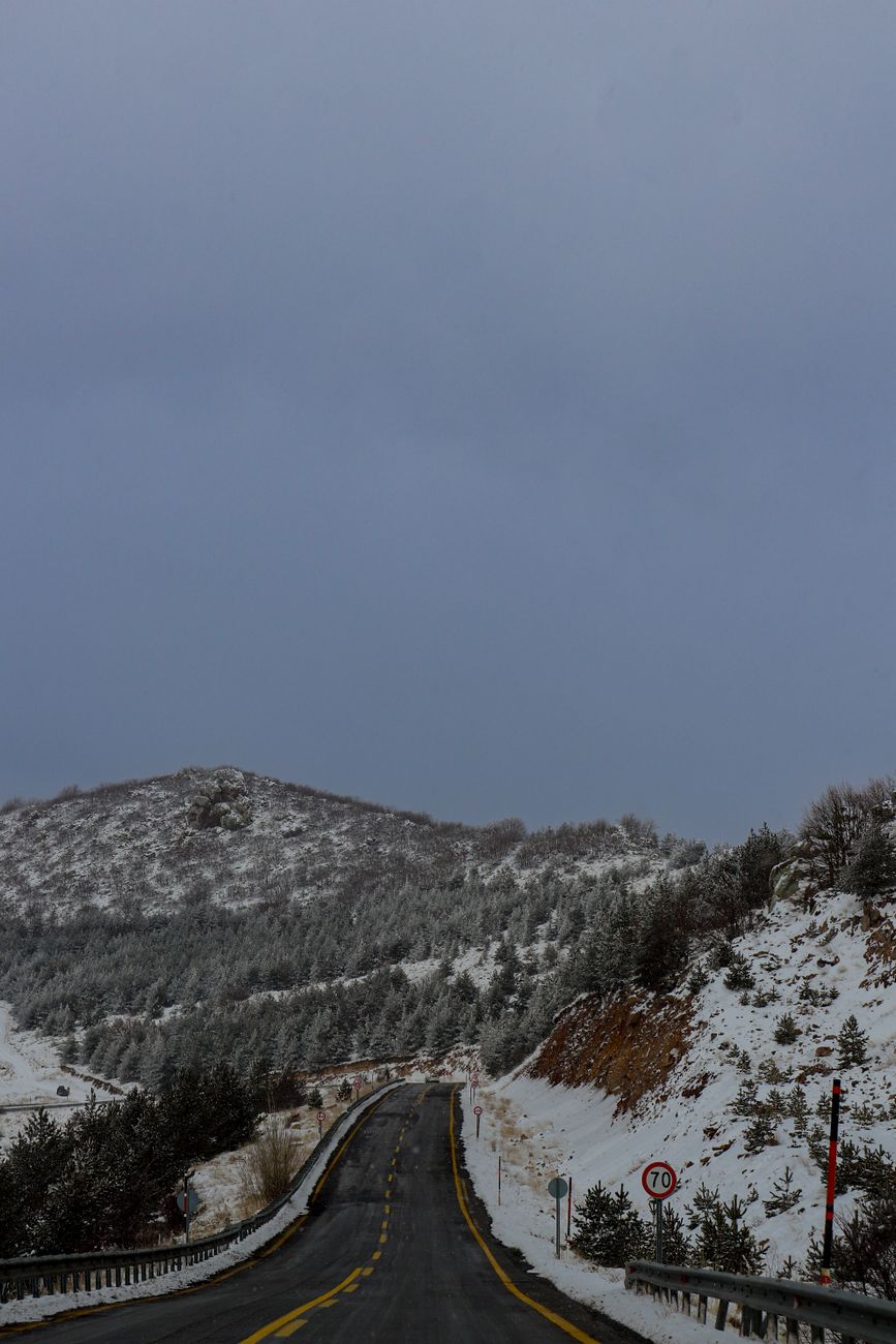 Cleared winter road cutting through snow-covered mountain terrain