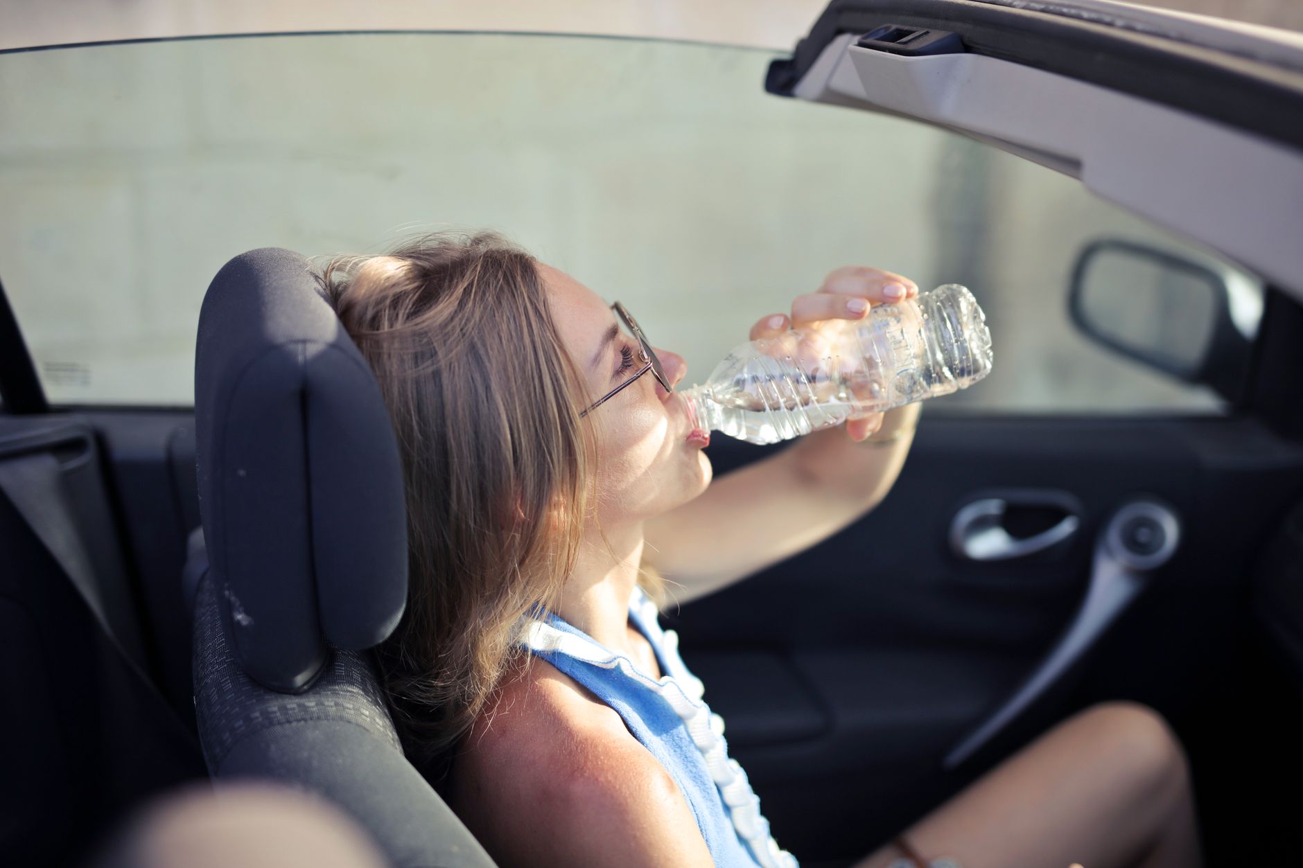 A woman in casual clothes drinking water outdoors